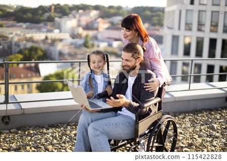 Happy family enjoying time together outdoors with a laptop Happy family enjoying time together outdoors with a laptop 115422828