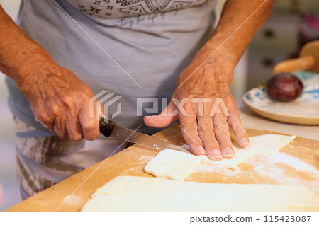 Preparation of homemade fruit dumplings with plums. Czech specialty of sweet good food. Dough on kitchen wooden table with hands. Preparation of homemade fruit dumplings with plums. Czech specialty of sweet good food. Dough on kitchen wooden table with hands. 115423087