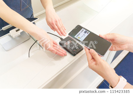 Customer and store clerk making a cashless payment 115423385