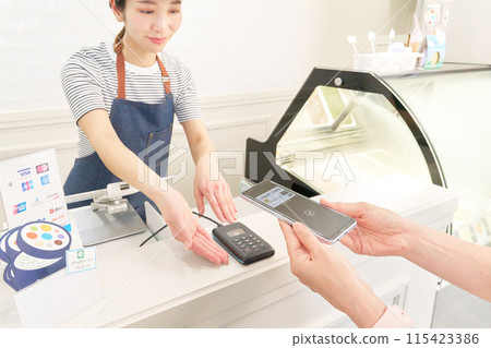 A store clerk explaining cashless payment and a customer holding up their smartphone A store clerk explaining cashless payment and a customer holding up their smartphone 115423386
