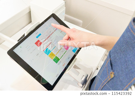 The hands of a store clerk operating a tablet cash register 115423392