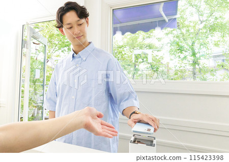 A young male customer making a cashless payment by holding up his smartphone 115423398