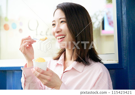Smiling young woman eating gelato 115423421