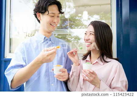 Smiling young man and woman eating gelato 115423422