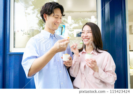 Smiling young man and woman eating gelato Smiling young man and woman eating gelato 115423424