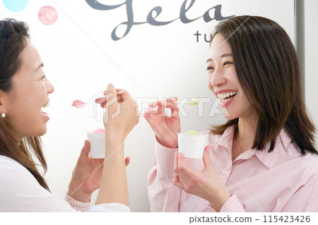 Two smiling women eating gelato 115423426