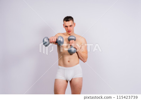 Shirtless bodybuilder holding dumbell and showing his muscular arms. 115423739