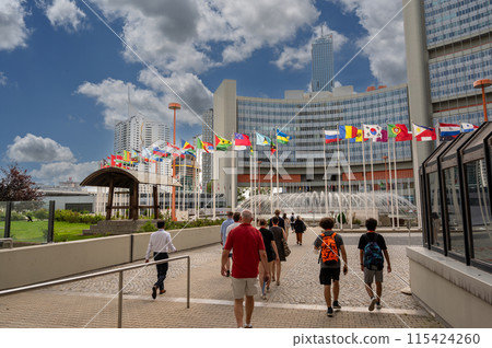 Vienna, Austria, August 17,2022. United Nations headquarters. Flags fly, visitors cross the courtyard. Beautiful summer day. Vienna, Austria, August 17,2022. United Nations headquarters. Flags fly, visitors cross the courtyard. Beautiful summer day. 115424260