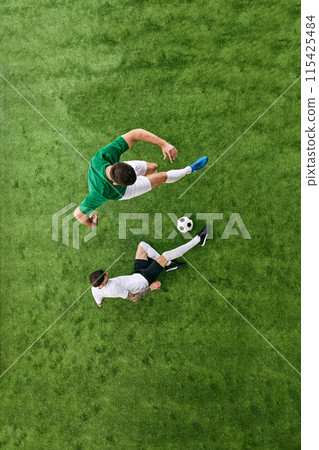 Aerial view of player in green attacking, while player in white defending on green lush playground. Football match. Aerial view of player in green attacking, while player in white defending on green lush playground. Football match. 115425484