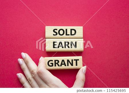 Sold Earn Grant symbol. Concept words Sold Earn Grant on wooden blocks. Businessman hand. Beautiful red background. Business and Sold Earn Grant concept. Copy space. 115425695