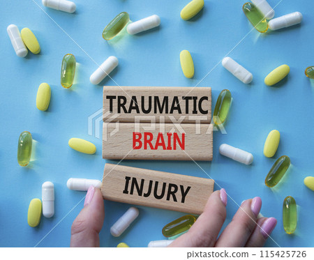 Traumatic Brain Injury symbol. Concept words Traumatic Brain Injury on wooden blocks. Beautiful blue background with pills. Doctor hand. Healthcare and Traumatic Brain Injury concept. Copy space. Traumatic Brain Injury symbol. Concept words Traumatic Brain Injury on wooden blocks. Beautiful blue background with pills. Doctor hand. Healthcare and Traumatic Brain Injury concept. Copy space. 115425726