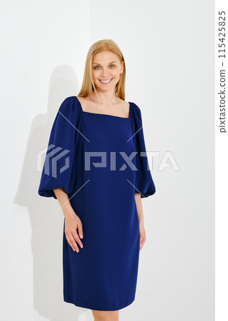 Medium closeup portrait of cute cheerful woman wearing blue dress with balloon sleeves Medium closeup portrait of cute cheerful woman wearing blue dress with balloon sleeves 115425825