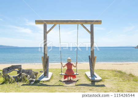 A woman riding a swing at the spectacular Maehama Beach [Minamishimabara City, Nagasaki Prefecture] 115426544