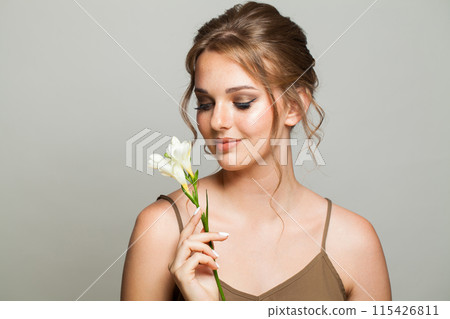 Portrait of beautiful young woman with clean fresh skin holding flower.  115426811