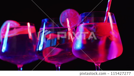 Glasses filled with vibrant drinks glow under neon lights 115427277