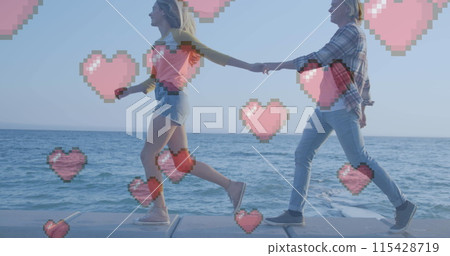 Multiple red heart icons floating against caucasian couple holding hands walking near the sea 115428719