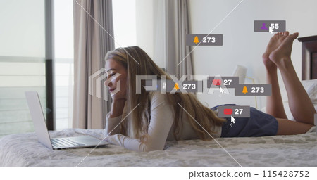 Image of network social media icons over smiling relaxing on bed using laptop 115428752