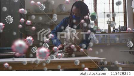 Image of virus cells over african american woman with face mask forming pottery 115429255