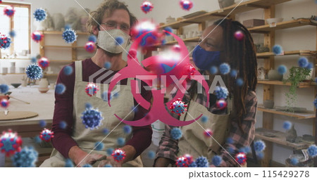 Image of virus cells and biohazard symbol over diverse workers with face masks 115429278