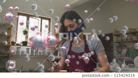 Image of virus cells over caucasian woman with face mask forming pottery 115429319