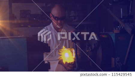 Image of glowing light over caucasian man working in workshop 115429545