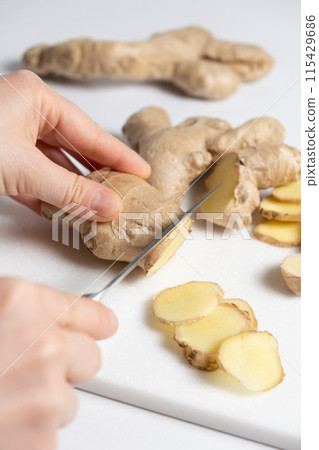 The process of cutting ginger root with a knife 115429686