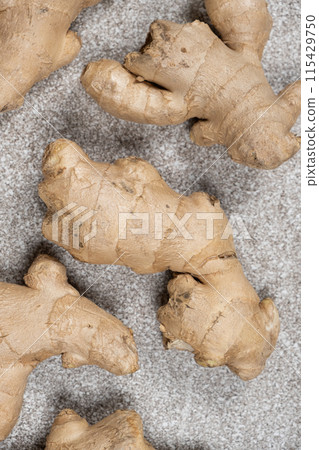 Fresh ginger roots on gray stone background close-up. Fresh ginger roots on gray stone background close-up. 115429750