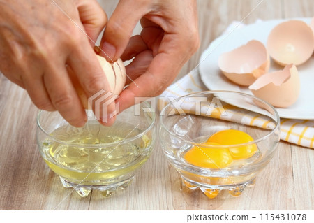 Woman hands breaking an egg to separate egg white and yolk. Woman hands breaking an egg to separate egg white and yolk. 115431078