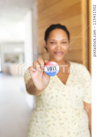 Young biracial woman holds a 'vote' badge, with copy space 115431502