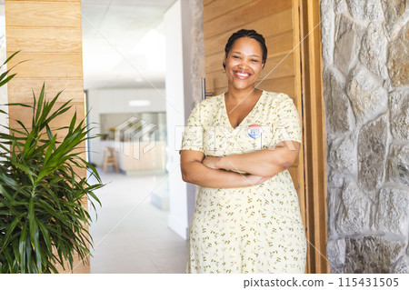 Young biracial woman stands confidently in a bright home setting, wearing a vote badge 115431505