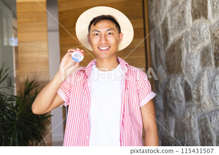Young Asian man shows a 'vote' badge proudly 115431507