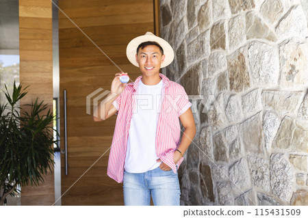 Young Asian man holding a vote badge stands by a stone wall, with copy space 115431509