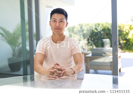 Young Asian man seated at a modern home office on a video call Young Asian man seated at a modern home office on a video call 115431535