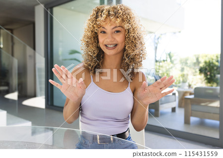 Young biracial woman smiles brightly at home on a video call 115431559