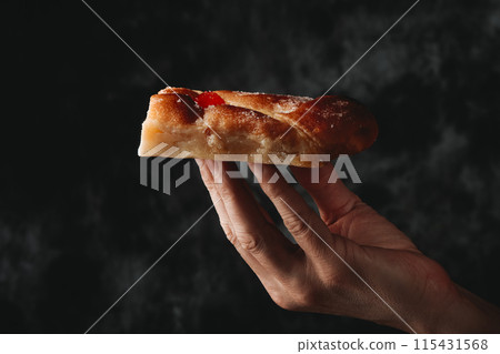 piece of catalan coca de sant joan in his hand 115431568