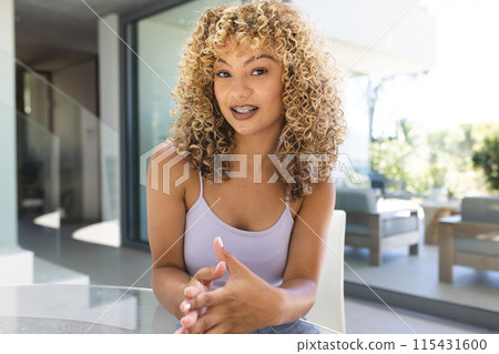 A young biracial woman smiles warmly at home on a video call 115431600