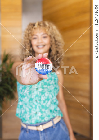 Young biracial woman shows a 'vote' button, with copy space Young biracial woman shows a 'vote' button, with copy space 115431604