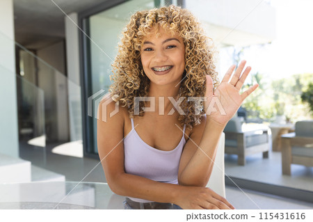 Young biracial woman smiles warmly at home on a video call 115431616