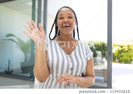 Young biracial woman waves cheerfully on a video call 115431618