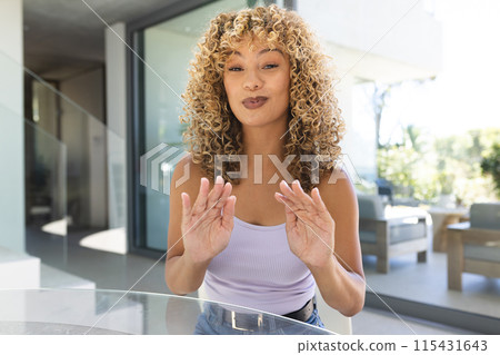 Young biracial woman blowing a kiss at home on a video call 115431643