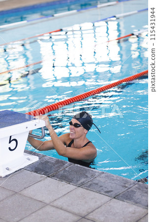 Caucasian female athlete swimmer prepares for a swim at an indoor pool 115431944