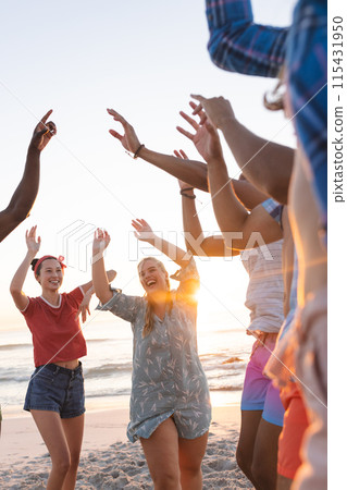Diverse young friends enjoy a beach party at sunset, with copy space 115431950