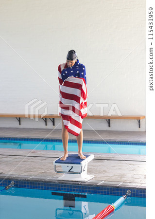 Caucasian female athlete swimmer wrapped in an American flag towel stands poolside 115431959