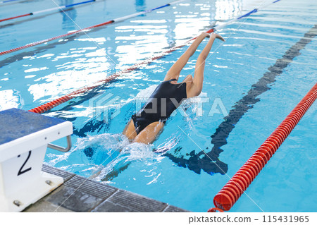 Caucasian female athlete swimmer dives into a swimming pool Caucasian female athlete swimmer dives into a swimming pool 115431965