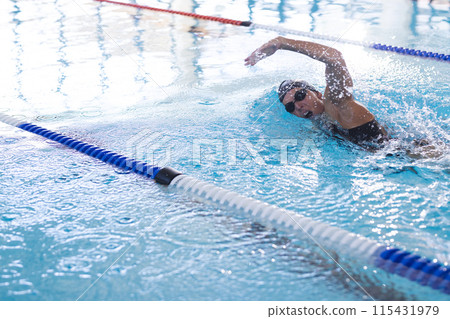Caucasian female athlete swimmer swims in an indoor pool 115431979