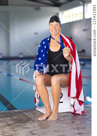 Caucasian woman draped in an American flag at a poolside, with medal, with copy space 115431991