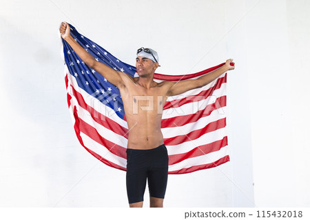 Young biracial male athlete swimmer holds an American flag with pride Young biracial male athlete swimmer holds an American flag with pride 115432018