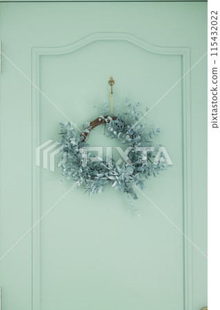 綠色門上裝飾的尤加利花環 115432022