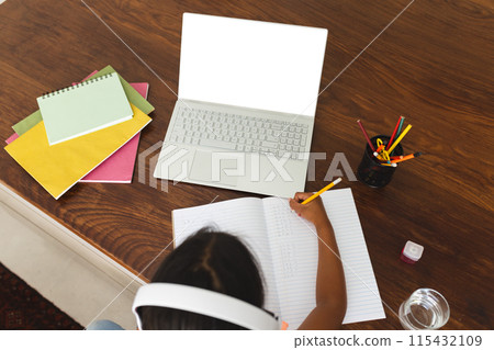 Biracial girl studies at home using a laptop, with copy space Biracial girl studies at home using a laptop, with copy space 115432109