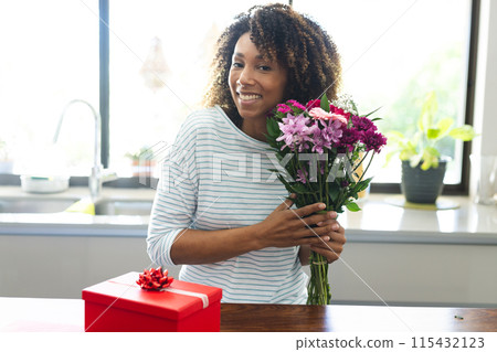 Biracial woman holding flowers at home during an online date video call Biracial woman holding flowers at home during an online date video call 115432123